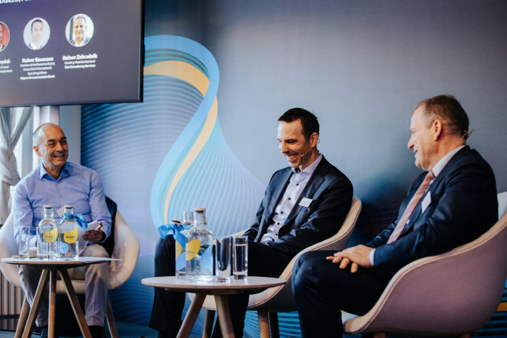 Drei Männer diskutieren auf einer Konferenz.